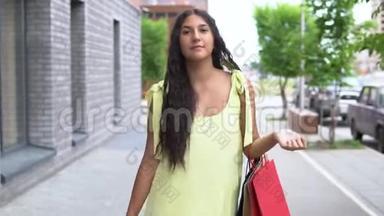 一个穿着黄色衣服的漂亮女孩在购物后走在街上。 慢动作。 高清高清